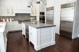 The white farmhouse sink blends well in this quaint colonial house design. White Kitchen With A Concrete Island And Dark Wood Floors Haus