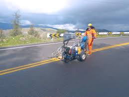 Ingeniero en Lima calculando el rendimiento de la pintura de tráfico por litro sobre un plano de carretera