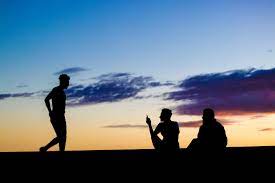Silhouettes Of A Small Group Of People Relaxing One Standing And Two Sitting Against A Partly Cloudy Sunset Photo Sky Friends Picture Frame