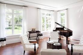 Large great room featuring a small black piano, comfy seats, a large fireplace and a bar area behind the seats. Piano Room Ideas How To Decorate A Room