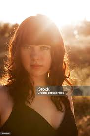 Portrait Of Young Woman In Field With Bright Sun Light Stock Photo