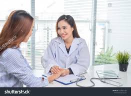 Female Doctor Talks To Female Patient In Hospital Office While Writing On The Patients Health Record On The Table Female Doctor Medical Services Stock Photos