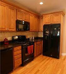 Black stainless steel appliances go well with colors that will either provide a high or low contrast. Oak Cabinet Design In Medway Ma Black Appliances Kitchen Kitchen Black Counter Brown Cabinets