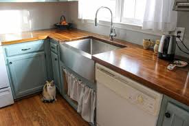 A lovely, fresh and simple kitchen makeover featuring light grey cabinets with a classic farmhouse sink and butcher block cabinets. Our Acacia Butcher Block Counters Blue Cabinets