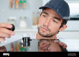 Male Repairman Installing Induction Cooker With Woman Standing In Kitchen  Stock Photo