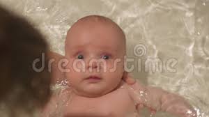 Your baby's first bath is one of the earliest milestones in your parenting journey, and a moment to treasure. Newborn Baby Boy Sneezes When Floundering In The Bathtub Supported By Mother Hands With Sparkle Of Water On Background Stock Footage Video Of Chubby Baby 172031186