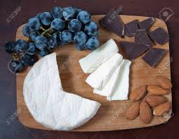 Brie Cheese On A Wooden Cutting Board With Grapes, Chocolate ...