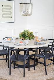 Round Wood And Iron Table Feature Black Wishbone Chairs On A Round Jut Rug Illuminated With A In 2020 Wood Floor Dining Room Round Wood Dining Table Brown Dining Room