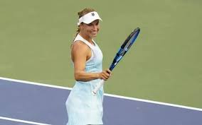 Tenista ucraniana Lesia Tsurenko sorri enquanto segura sua raquete em uma quadra de tênis.