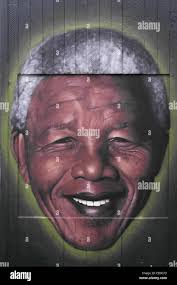 Portrait smiling head of Nelson Mandela painted end of old toilet block by  graffiti artist Akse, Stevenson Square, Manchester Stock Photo