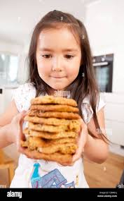 Young girl staring intently at stack of large homemade cookies Stock Photo 