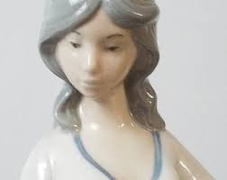 Rex Valencia porcelain figurine of a young woman standing beside a duck.  She is holding a shallow basket, presumably filled with duck feed.