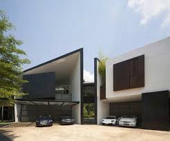 This is a funky, unique house with a black and white exterior with a bright red door. Black White House By Formwerkz Architects