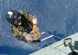 Explosive Ordnance Disposal Technician 2nd Class Jonathan Tatman ascends a  caving ladder to an HH-60H Sea Hawk helicopter.
