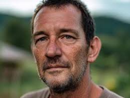 uma pessoa com uma barba sorrisos suavemente, banhado dentro caloroso  iluminação, com borrado luzes dentro a fundo. a imagem exala uma acolhedor  e convidativo atmosfera, concentrando em a assuntos face 72702676 Foto