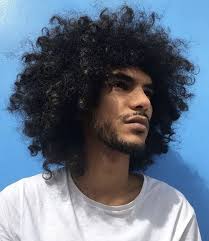 This curly hairstyle is perfect for women who need a hair routine that isn't complicated and want their natural texture to exist effortlessly. A Photograph Of A Black French Male With Long Kinky Curly Hair Tousled Into A Fashionable Big Hairstyle By Using A Blow Dryer And A Hairstyling Cream Long Hair Guys