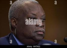 Governor of the Virgin Islands Kenneth E. Mapp,left, and her husband Chief  Warrant Officer 5 (ret.) Dennis Howell, right, replace the shoulder boards  of Adjutant General of the Virgin Islands Brig. Gen (