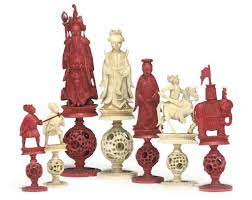 Chinese carved ivory (puzzle ball below figures), chess set, c. A Chinese Export Carved Ivory Puzzle Ball Figural Chess Set