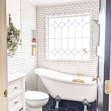 White subway tile shower with patterned accent in dark bathroom with white tub and black tile flooring. 32 Beautiful Bathroom Tile Design Ideas