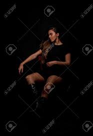 娼婦に座ってスタイリッシュな服を着てポーズをとる魅力的な女性のスタジオボディショットの写真素材・画像素材 Image 179958254