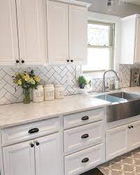 Light and bright, this transitional kitchen features white shaker style cabinets, gray stone countertops, a farmhouse sink and a white and gray glass tile backsplash. 25 Gorgeous Modern Farmhouse Kitchens Decoratoo Farmhouse Kitchen Backsplash Farmhouse Kitchen Decor New Kitchen Cabinets