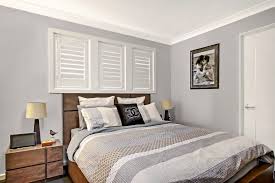 Incredible bedroom with gray wall to wall carpeting pairing with graphic dark blue and white paisley wallpaper which frames the plantation shuttered windows. Plantation Shutters Vs Curtains And Blinds Which Is Better Modern Group