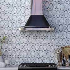 Fantastic kitchen features a dual farmhouse sink paired with a satin nickel gooseneck faucet alongside a marble hex tiled backsplash. Marble Hex Tile Backsplash Design Ideas