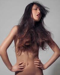 Portrait of nude young woman, long hair covering breasts, hands on hips  stock photo