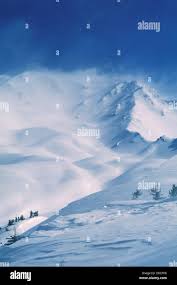 Wind blowing snow off mountain hi-res ...