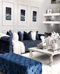 A calming blue dining room with blue and gray chairs, a glass table for six, and a silver chandelier. Home Decor Interior Design On Instagram Happy Monday Who Is In Love With This Tufted Beaut Navy Sofa Living Room Blue Living Room Decor Silver Living Room