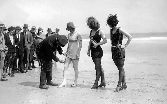 Vintage photo of policeman measuring women's swimwear in 1920