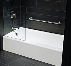 An arched living room alcove is filled with black cabinets fitted with a glass front wine cooler topped with black marble framing a wet bar sink and gooseneck faucet alongside a mosaic tiled mirrored mirrored backsplash illuminated by a fringe. Bellweather Tub Like How Clean The Side Is Tub Shower Combo Bathroom Improvements Bathtub Remodel