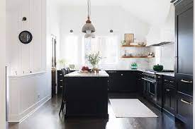 Black kitchen cabinets are tempered here with the light wood island and countertops. The Black Kitchen Cabinet Trend Heather Hungeling Design