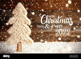 Merry Christmas And Happy New Year 2022 In Spanish English Calligraphy Merry Christmas And A Happy 2022 White Fabric Christmas Tree With Snow Brown Rustic Wooden Background With Snowflakes Stock Photo Alamy
