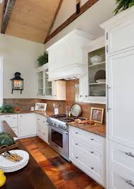 Contemporary kitchen with white frameless cabinets paired with white and gray marble countertops and matching backsplash framing white dome hood over wolf range across from clear glass pendants over marble top island with dual sink lined. Granite Backsplash How To Choose Between 4 Full Height