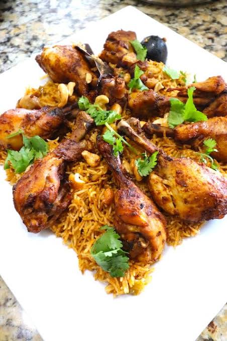 Beautifully plated Instant Pot Kabsa topped with golden roasted chicken garnished with toasted almonds pine nuts and golden raisins on a festive serving dish