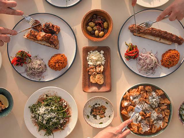 Family hands reaching for Iftar dishes traditional Ramadan meal atmosphere