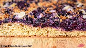In step two of the recipe, a sugar, flour and cinnamon mixture is sprinkled over the blueberries, which leaves a few pockets of undissolved sugar on top of the filling after baking. German Blueberry Kuchen The Delicious Crescent