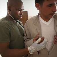 Ensign Jerry McNew, an information officer with 6th Marine Regiment, 2nd  Marine Division, II Marine Expeditionary Unit, provides security while  Iraqi police officers and Army Soldiers hand out food supplies.