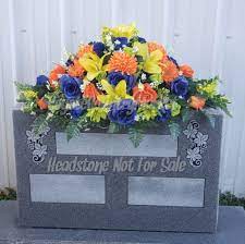 Artificial flower bouquets that are secured in a plastic vase designed to stick in the ground next to a grave. Cemetery Headstone Saddle Cemetery Flowers Grave Flowers Headstone Flowers Cemetery Arrangement Grave Decoration Tombstone Saddle Grave Decorations Cemetery Flowers Memorial Flowers