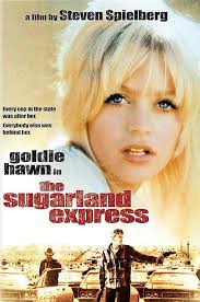 The Sugarland Express (1974)** A woman attempts to reunite her family by  helping her husband escape prison and together kidnapping their son. But  things don't go as planned when they are forced