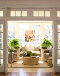 Crisp Sunroom With Transom Windows Light Colored Wicker White And Beige Cushions Green Ferns And Plants Spa Sunroom Designs Sunroom Decorating Garden Room