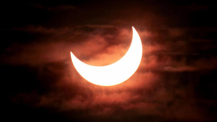 A silhouette of the moon partially obscuring the sun during a total solar eclipse event.