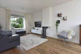 donkergrijze bank grijze fauteuil houten vloer wit en groene plant donkergrijze bank houten vloer interieur