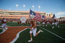 The Texas Football Team Carries The American Flag Onto The Field During Pregame Ceremonies Texas Football Travel Channel Longhorns Football