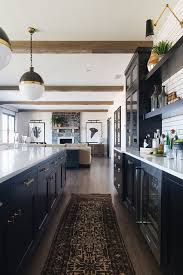 Farmhouse Black Cabinet Kitchen With Vintage Runner And Beams More Source On Home Bunch B Modern Farmhouse Kitchens Home Decor Kitchen Interior Design Kitchen