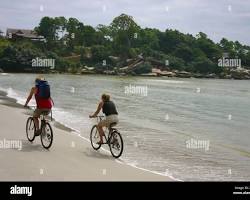 Couple cycling along a sandy beach in Sihanoukville