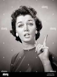 Anni Cinquanta anni sessanta BRUNETTE DONNA PEARL STRAND ORECCHINI puntare  il dito fino a Parlare Parlare guardando la telecamera LECTURE INSEGNARE  NAG