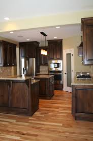 The dark finishes on the farmhouse sink and the towel rack also highlight the richness of the wood floor. Carstensen Homes Hickory Kitchen Cabinets Kitchen Flooring Wood Floor Kitchen