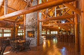 Interior of Pine Barrens Golf Club's rustic wooden clubhouse with stone fireplace and dining tables.